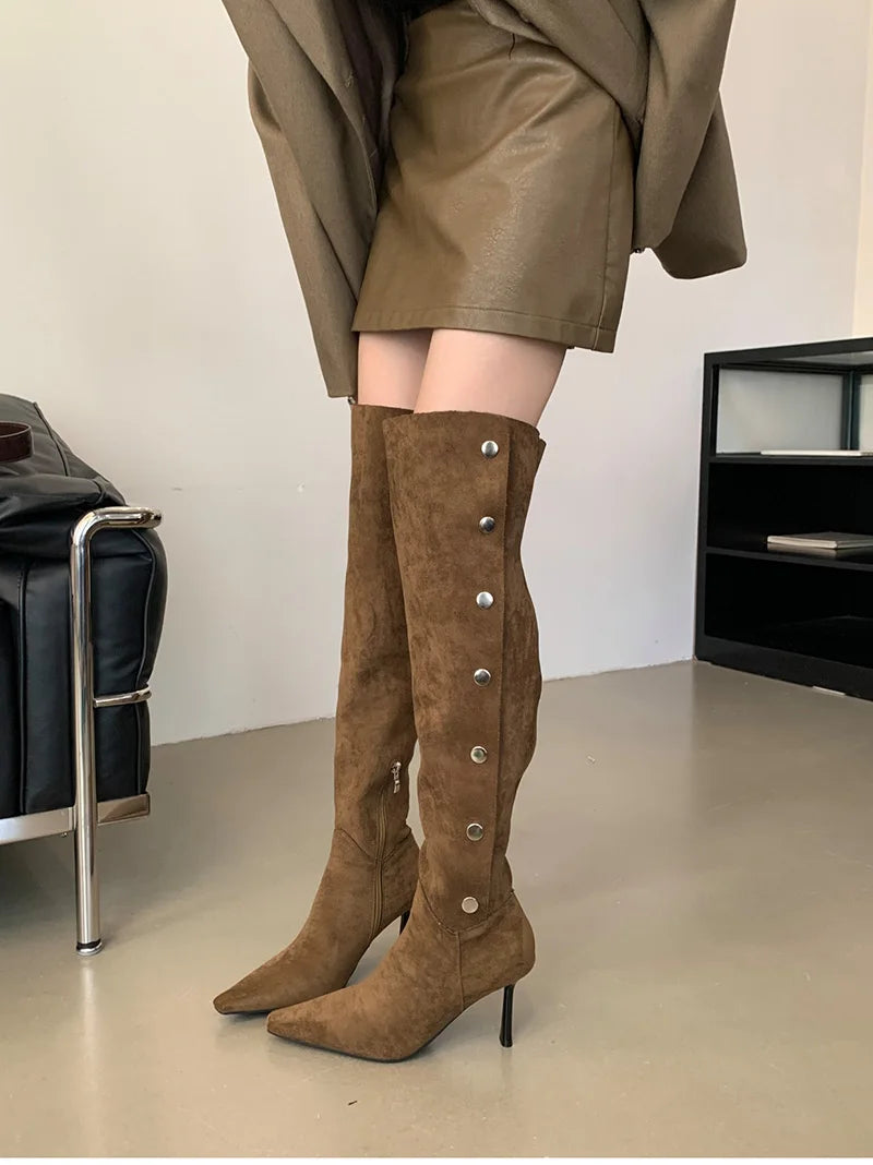 Brown suede knee-high boots with silver buttons worn by a person in an indoor setting.