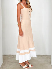 Woman wearing a beige and white dress against a plain background