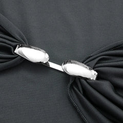 Close-up of a black garment with a bow and silver clasp on a dark background