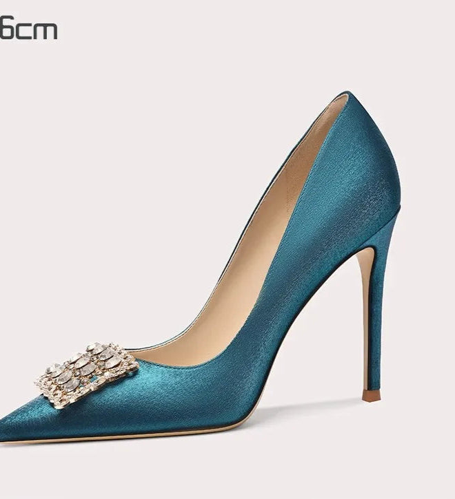 Blue high-heeled shoe with a decorative brooch on a white background