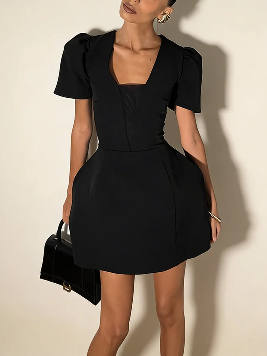 Woman wearing a black dress with puff sleeves against a beige background