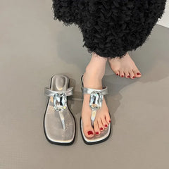 Model wearing silver square toe flat sandals with a black skirt.