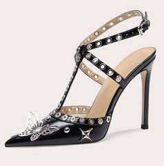 Black high-heeled shoe with decorative straps and embellishments on a white background