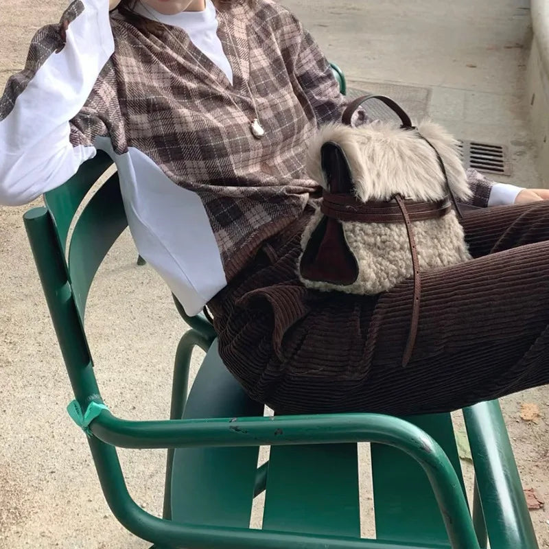Person sitting with a plush fur belted messenger bag on a chair.