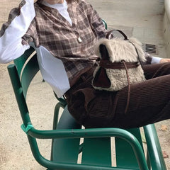 Person sitting with a plush fur belted messenger bag on a chair.