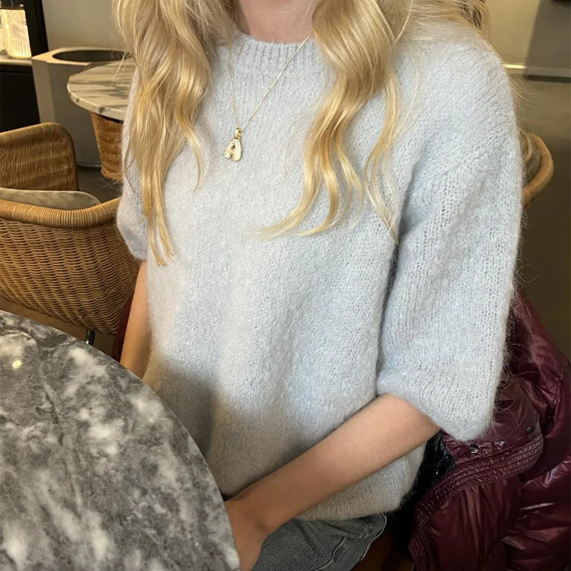 Person wearing a light gray sweater in an indoor setting