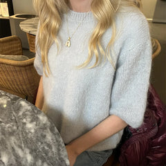 Person wearing a light gray sweater in an indoor setting