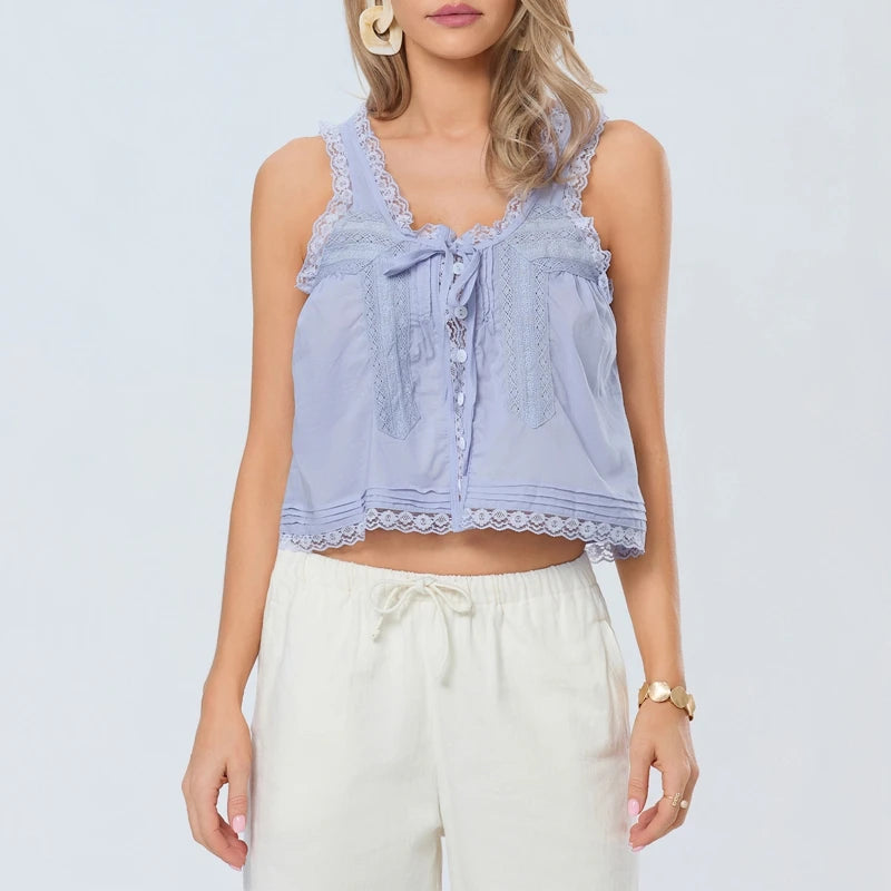 Woman wearing a light blue lace-trimmed top with a plain background