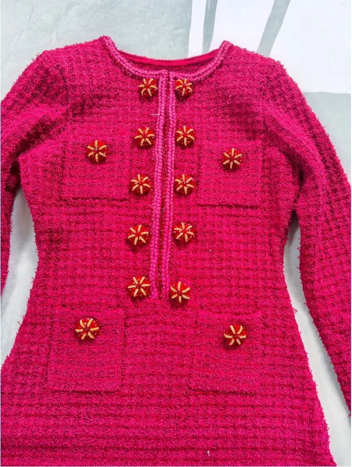 Pink knitted sweater with decorative buttons on a white background