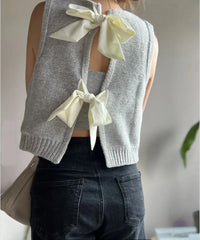 Gray knitted vest with white bows on a blurred background