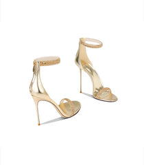 Gold high-heeled shoes with open-toe design on a white background
