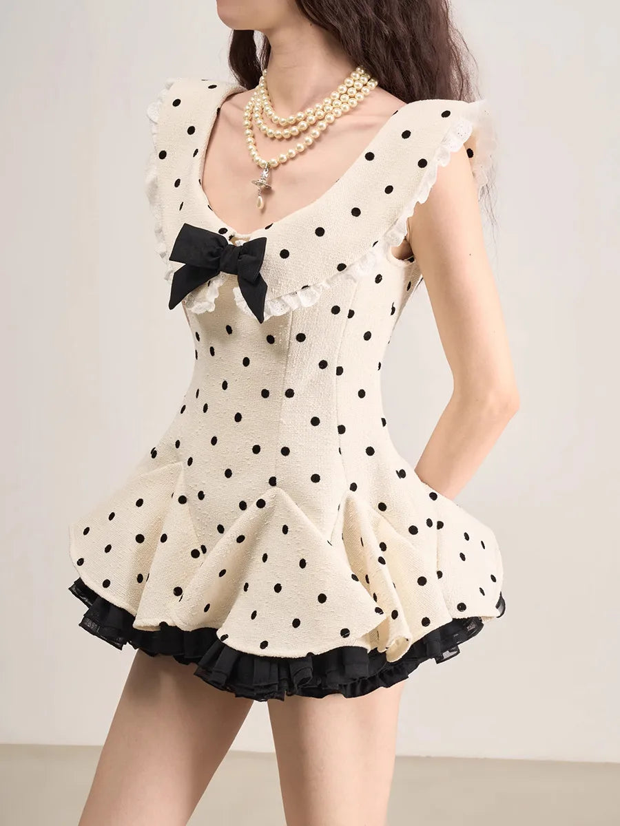 White polka dot dress with black details and a bow on a plain background