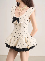 White polka dot dress with black details and a bow on a plain background