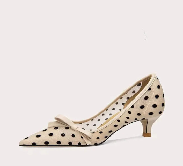 Beige high-heeled shoe with polka dot pattern and bow on a white background