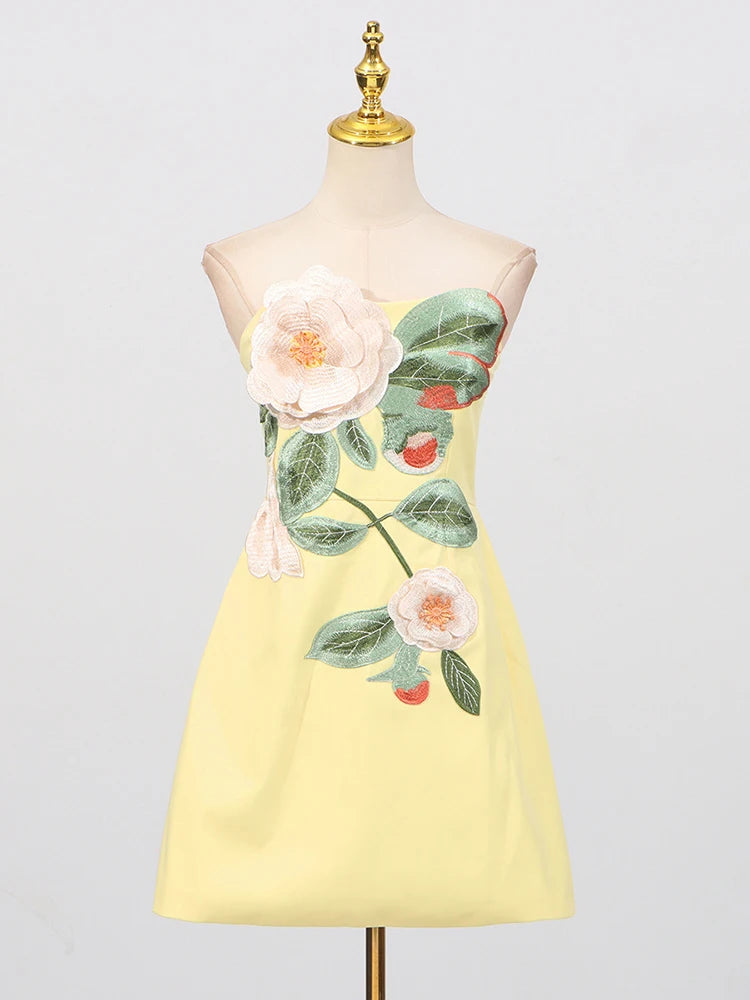 Yellow dress with floral design on a mannequin against a light gray background