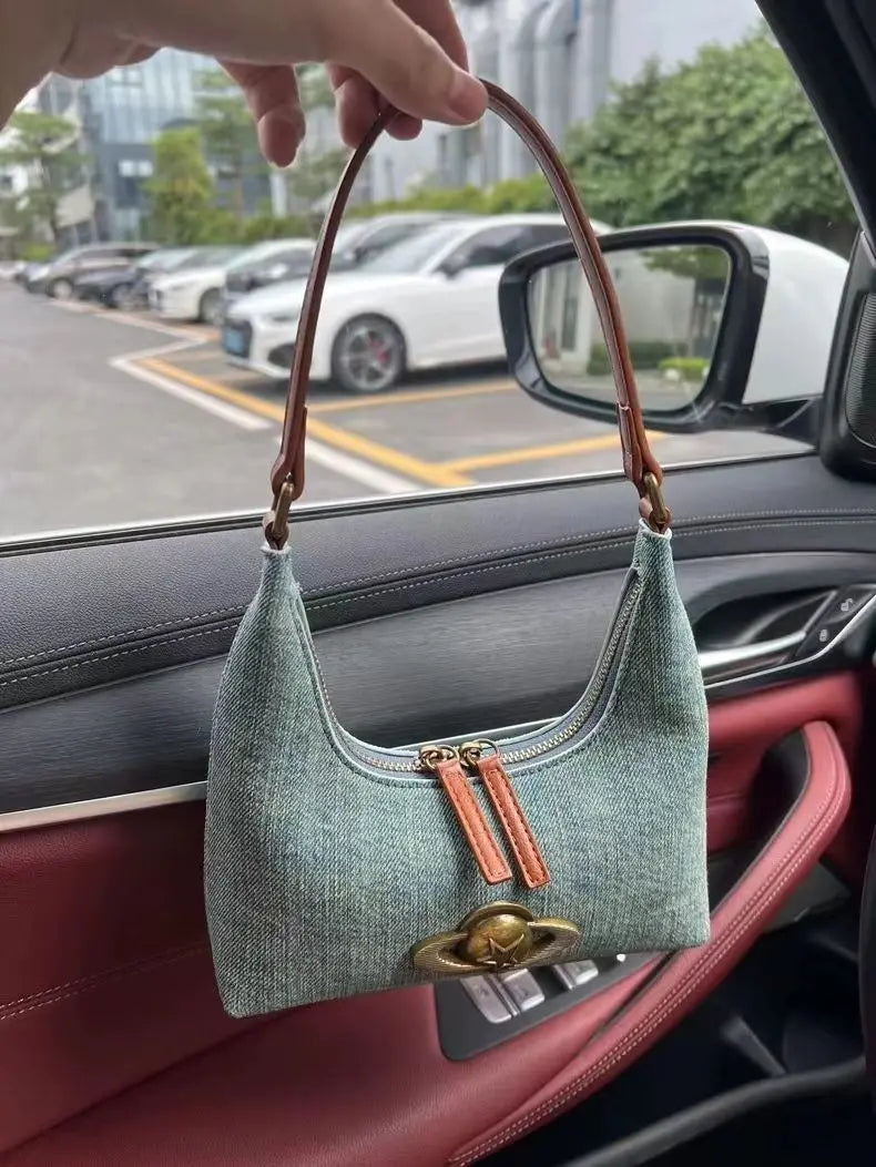 Green handbag held by a person inside a car with a cityscape background