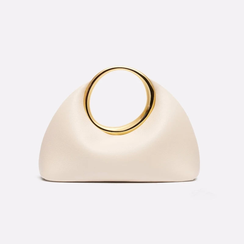 Cream-colored handbag with a gold circular handle on a light gray background