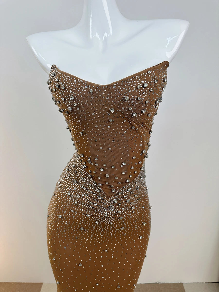 Gold evening gown with rhinestone embellishments on a mannequin against a white background