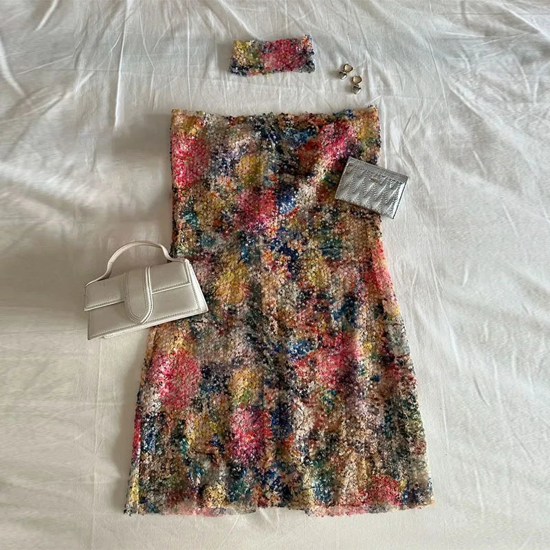 Colorful sequin skirt with a handbag and jewelry on a white surface