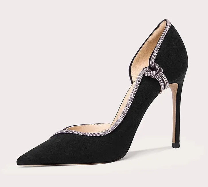 Black high-heeled shoe with decorative bow on a light gray background