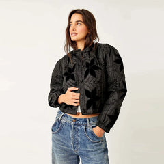 Woman wearing a black patterned jacket and blue jeans on a white background