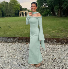 Woman in a light green off-shoulder dress standing in a park.