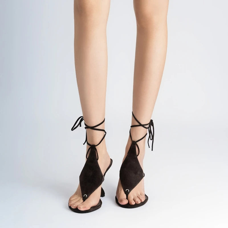 Black strappy sandals worn on a white background