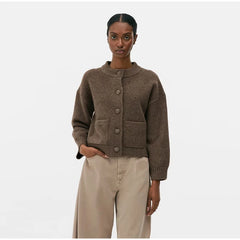 Woman wearing a kase knitted cardigan and beige pants on a white background