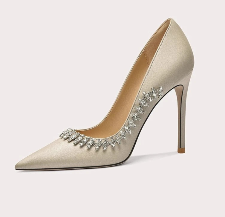 Beige high-heeled shoe with embellishments on a light gray background