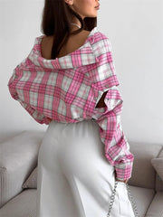 Person wearing a pink and white plaid shirt with cut-out design, sitting on a couch.