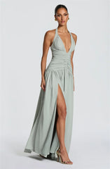 Woman wearing a light green halter neck gown with a high slit on a white background