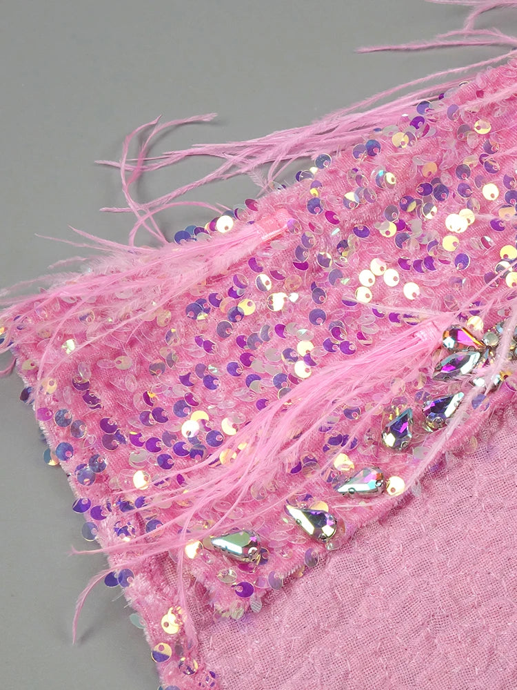 Close-up of pink fabric with sequins and tassels on a gray background