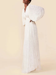 Woman wearing a white dress with textured sleeves against a beige background