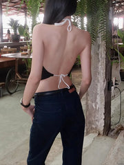 Person wearing a black bikini with white straps in an outdoor setting