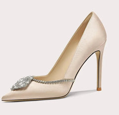 Beige high-heeled shoe with decorative element on a light gray background