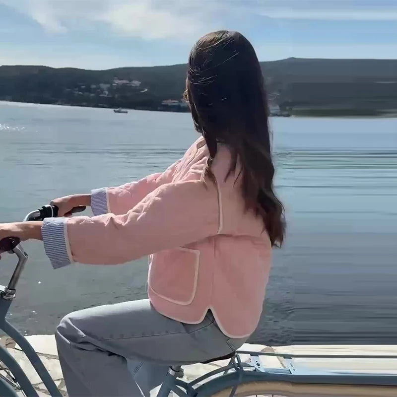 Person sitting on a bicycle by a lake with mountains in the background