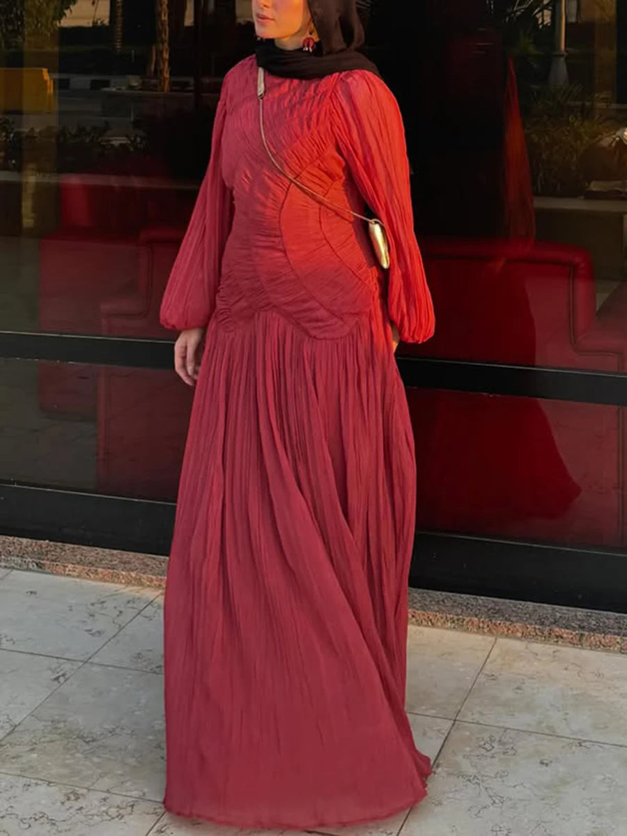 Person wearing a long red dress standing in front of a reflective surface.
