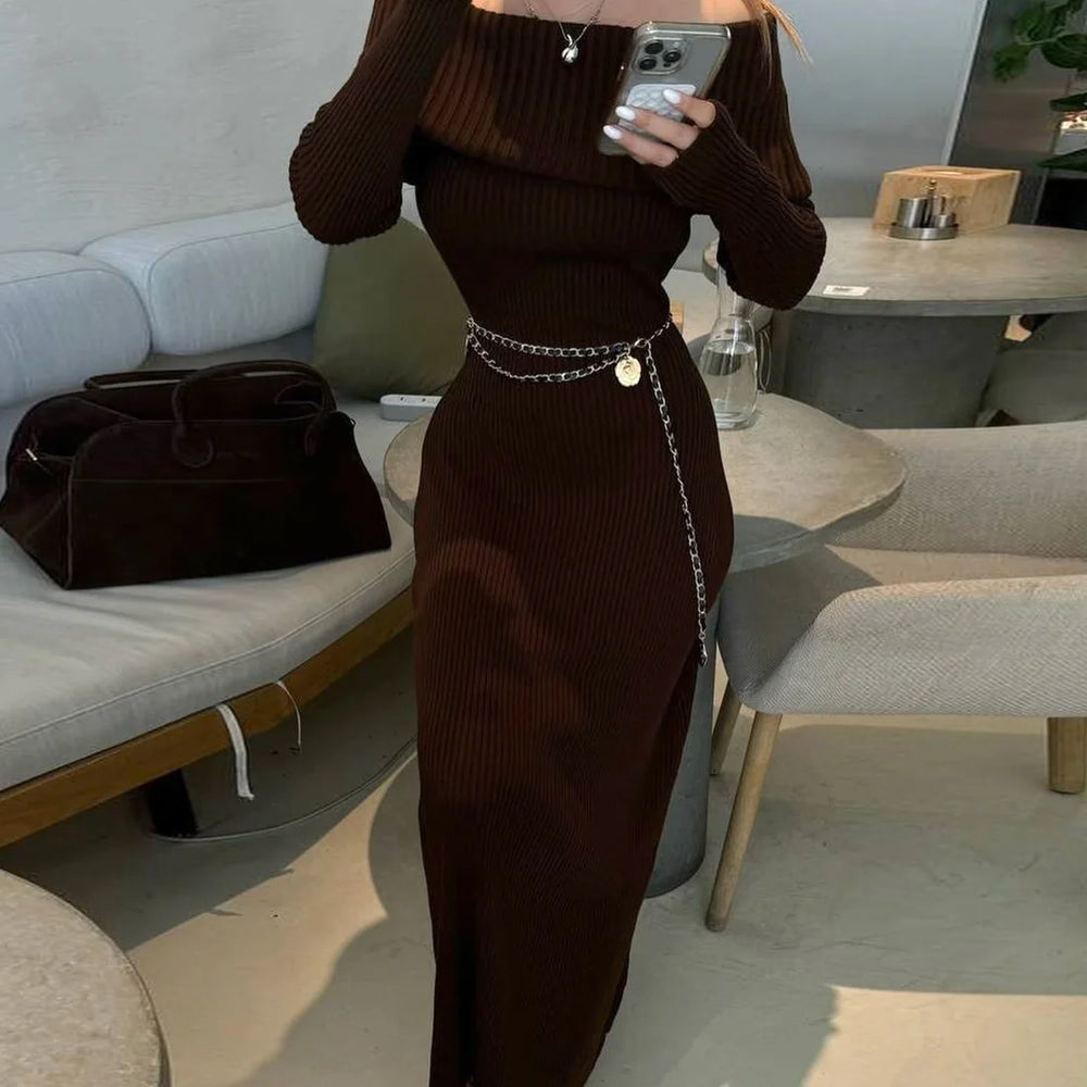 Person wearing a brown ribbed dress with a chain belt in a living room setting.
