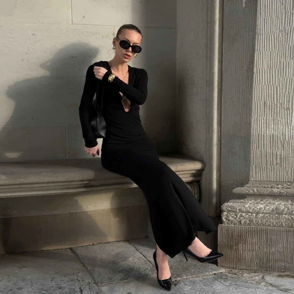 Woman in a black outfit sitting on stone steps wearing sunglasses.