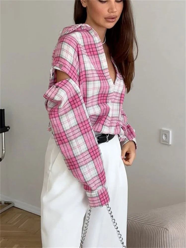 Person wearing a pink and white plaid shirt with cut-out sleeves in an indoor setting.