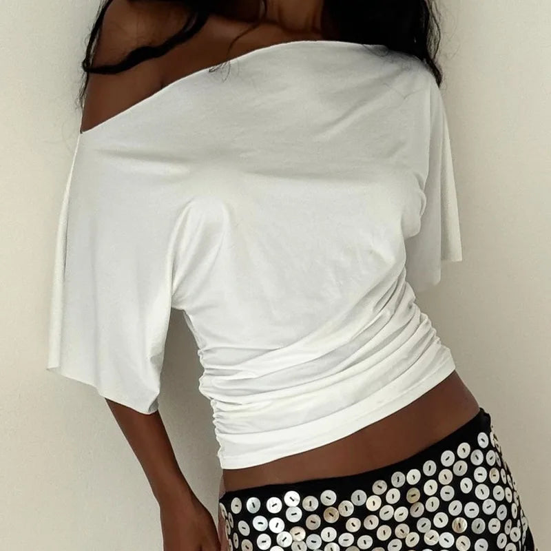 Person wearing a white off-shoulder top with a plain background