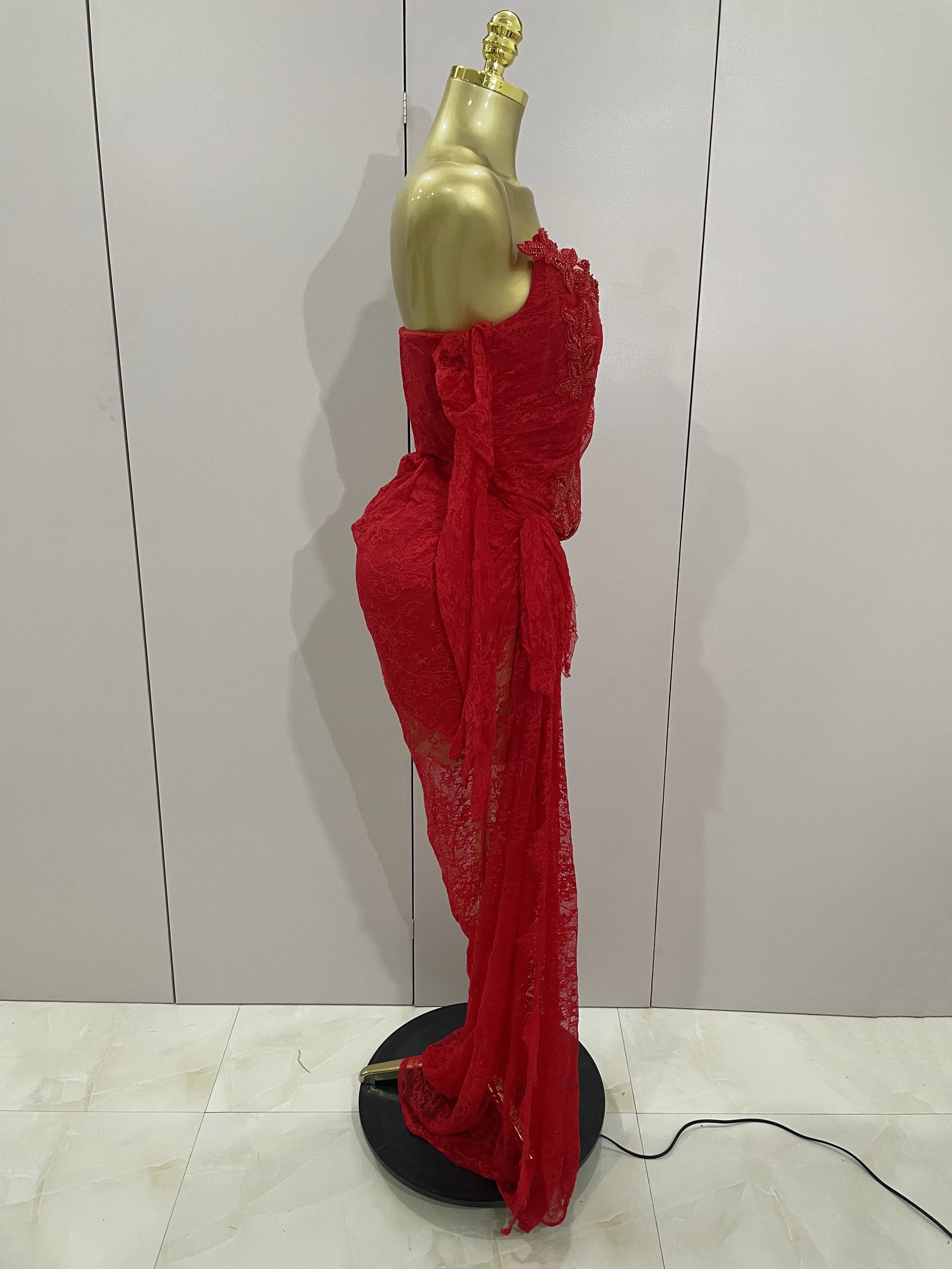 Red lace dress on a gold mannequin against a white wall.