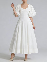 White dress with puff sleeves on a plain background