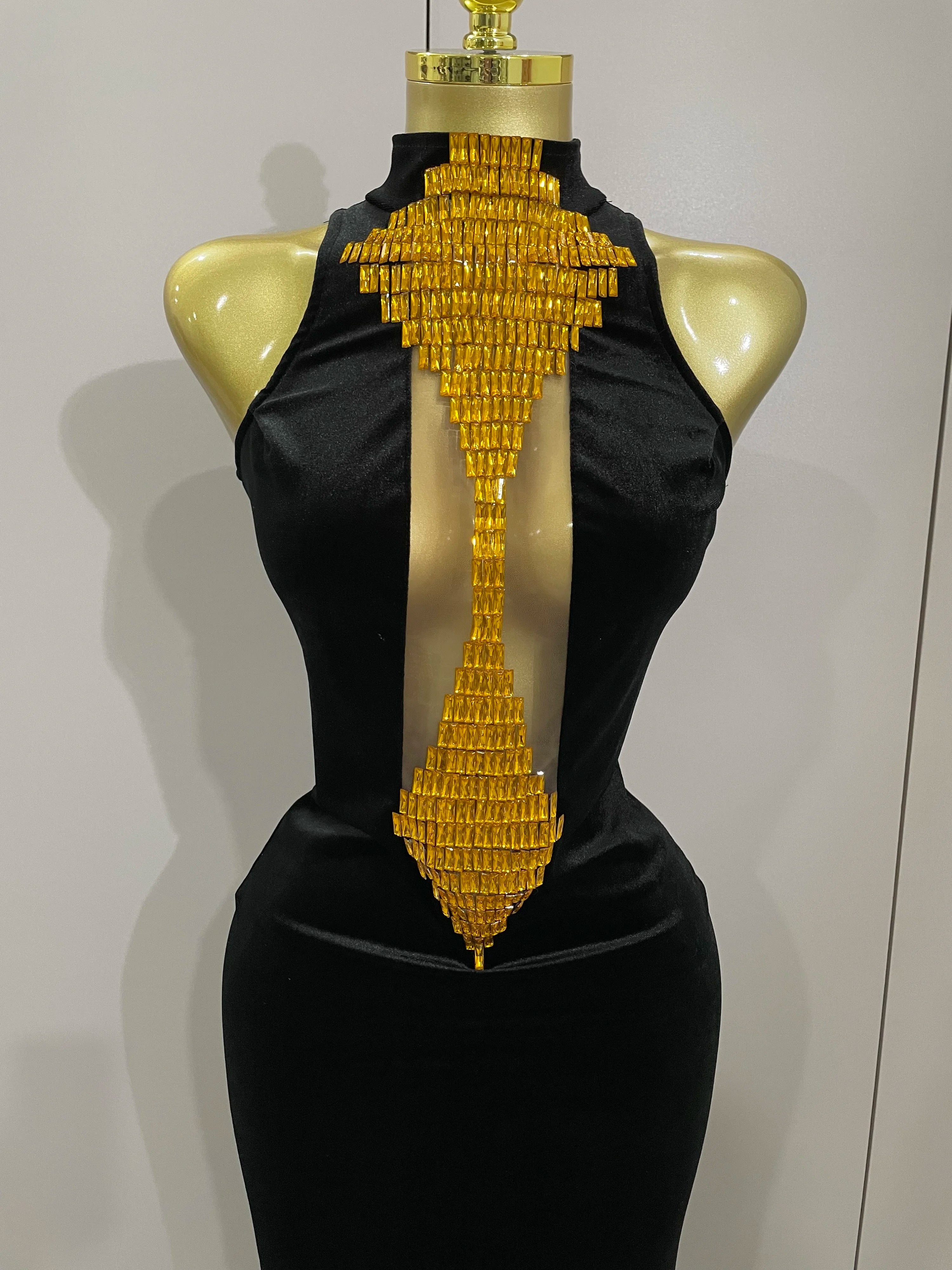 Black dress with gold geometric back design on a mannequin against a plain background
