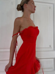 Woman wearing a red one-shoulder dress against a white door background