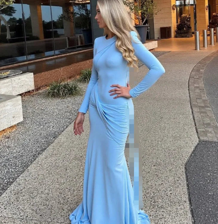 Woman in a light blue evening gown standing on a sidewalk.