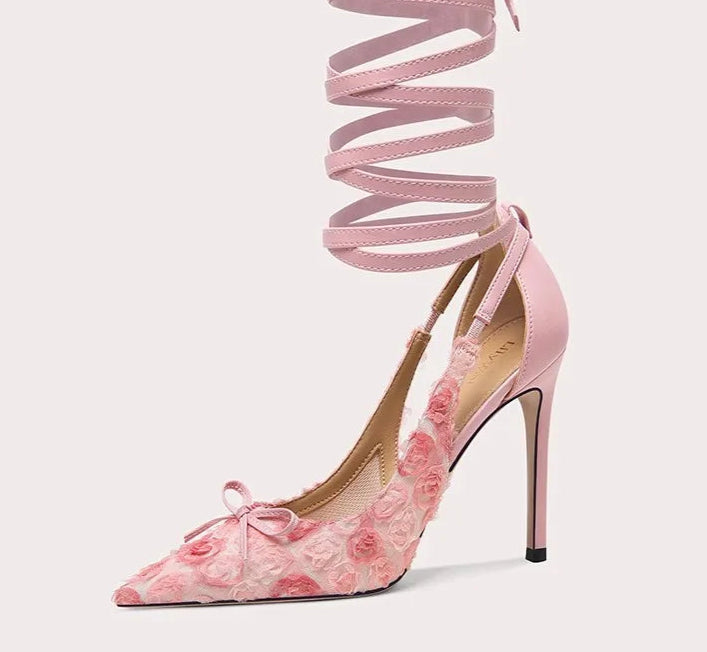 Pink high-heeled shoe with floral design and ribbon on a white background