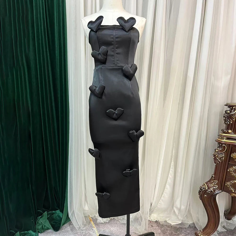 Black dress with heart-shaped cutouts on a mannequin against a curtain backdrop