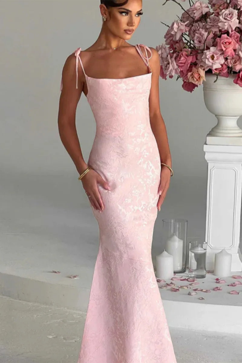 Woman wearing a pink lace dress in an elegant indoor setting with flowers and candles.