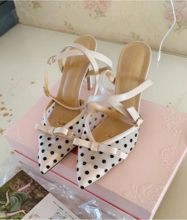 Polka dot high-heeled shoes on a pink surface with a magazine underneath